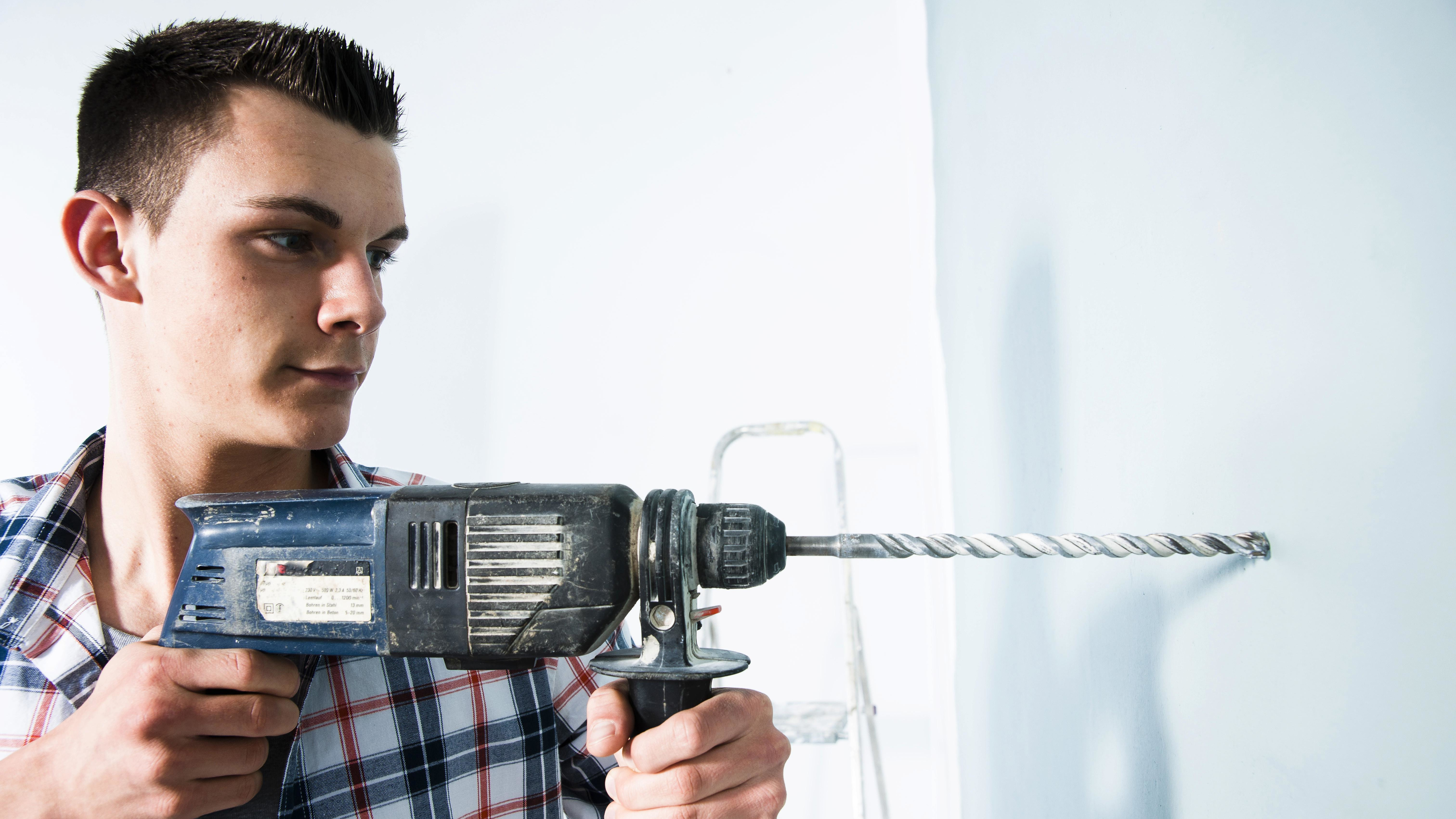 Man drilling a blue wall
