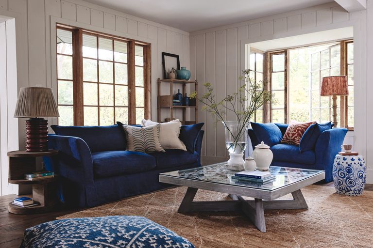 blue room with blue sofa and armchair, shiplap walls, rug, coffee table, table lamps 