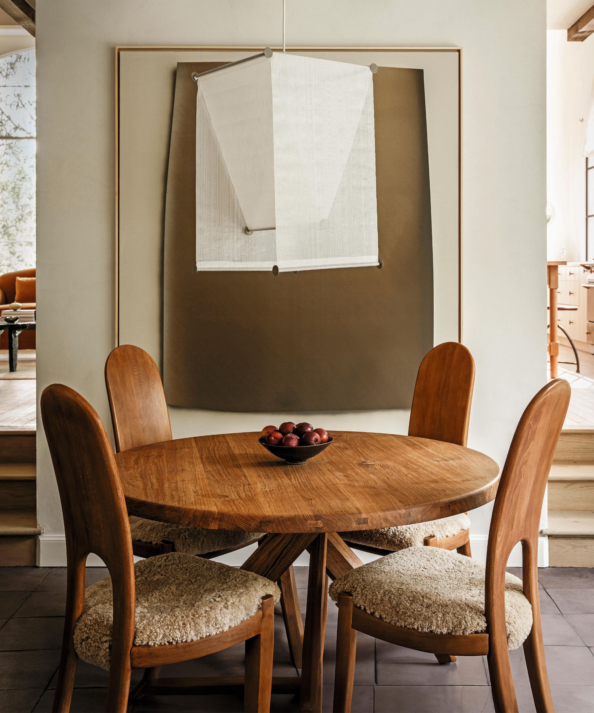 a neutral vintage style small breakfast nook with abstract art and linen ceiling pendant