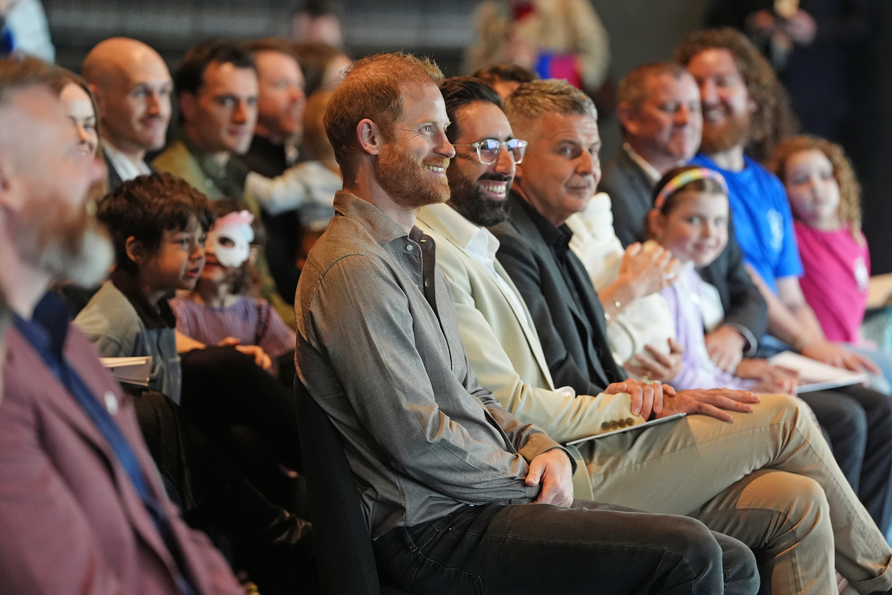 Prince Harry sitting in an audience and smiling
