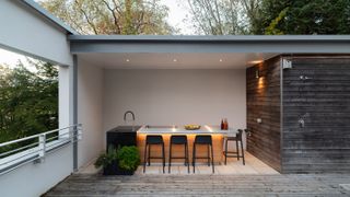 undercover outdoor kitchen with island units and stools