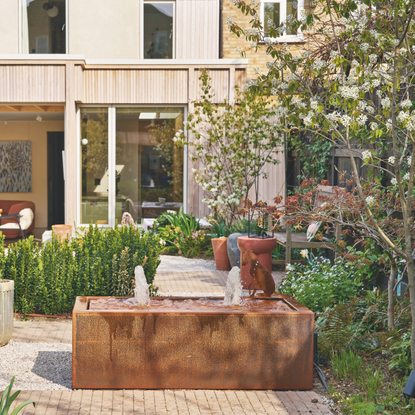 Exterior view of the house and garden with a water feature and gravel paths.