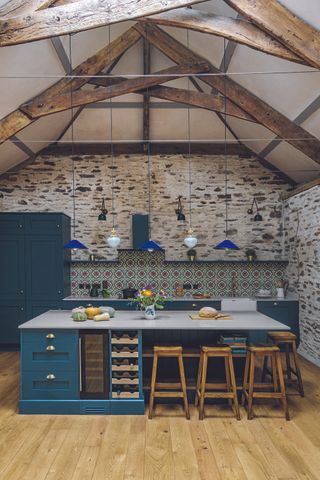 interior of barn conversion with modern blue kitchen and stone walls