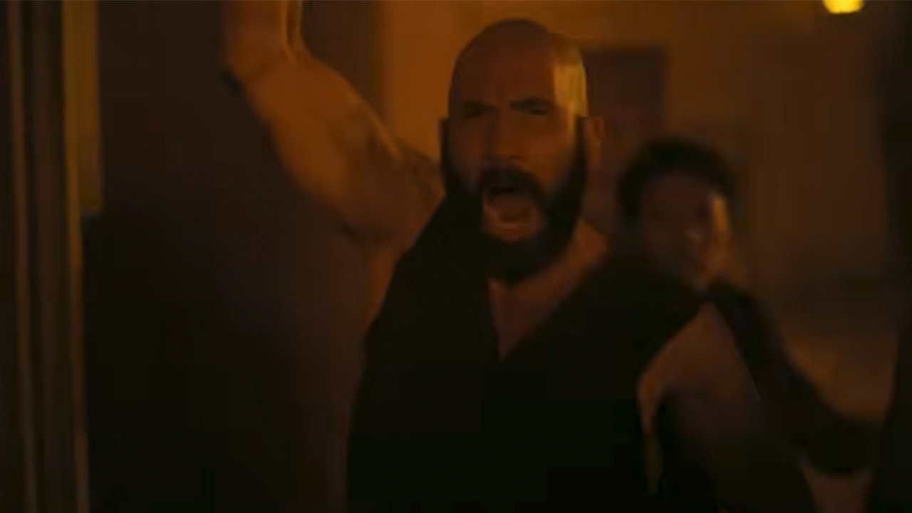 Jon Bernthal with a thick black beard, raising his arm and yelling in The Odyssey