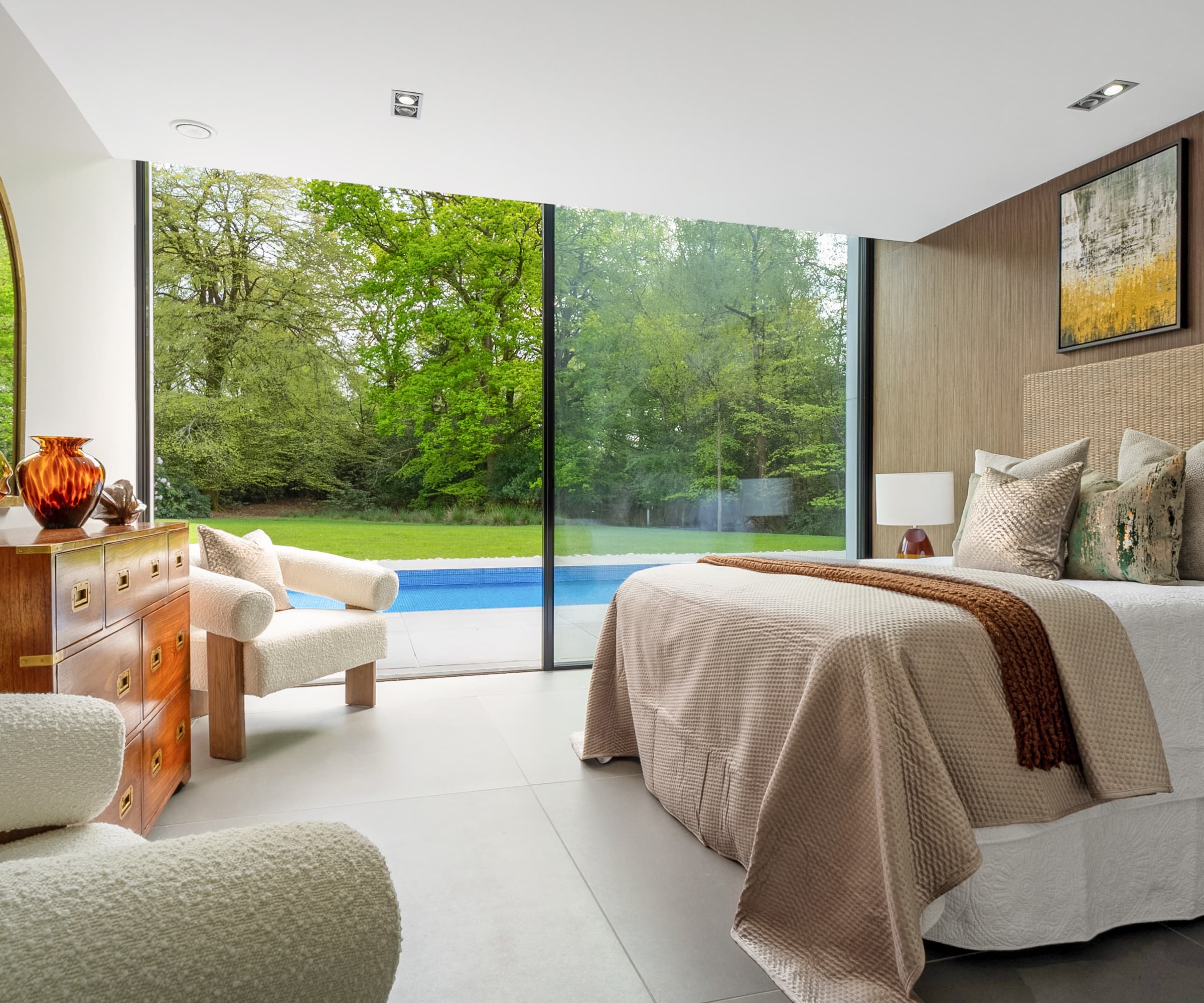 A bedroom with bifold doors to a swimming pool