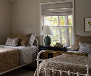 neutral bedroom with twin iron beds and yellow quilts