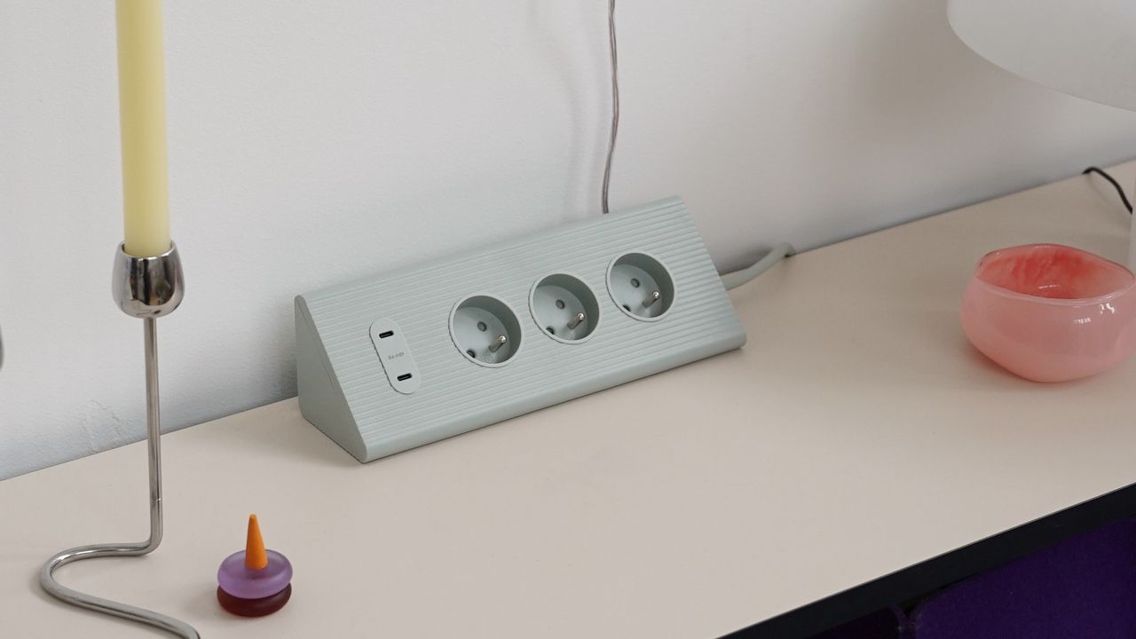 IKEA&#039;s SKOTAT extension cord on a sideboard with a chrome candlestick and a decorative glass bowl next to it