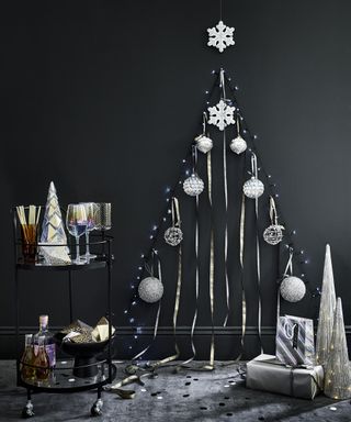 A wall painted with black wall paint and decorated with silver baubles and gift ribbon