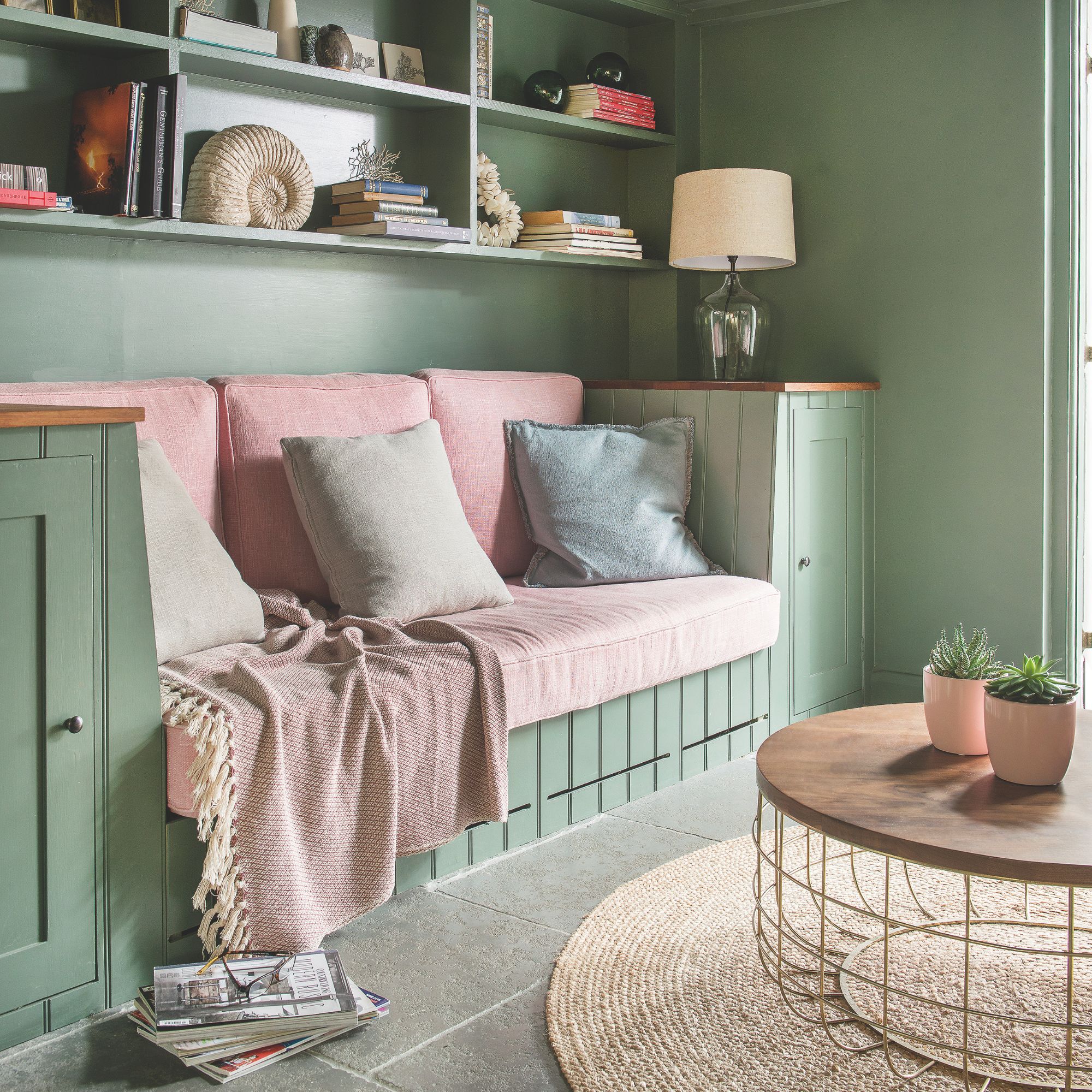 A green bench sofa with pink cushions and throws