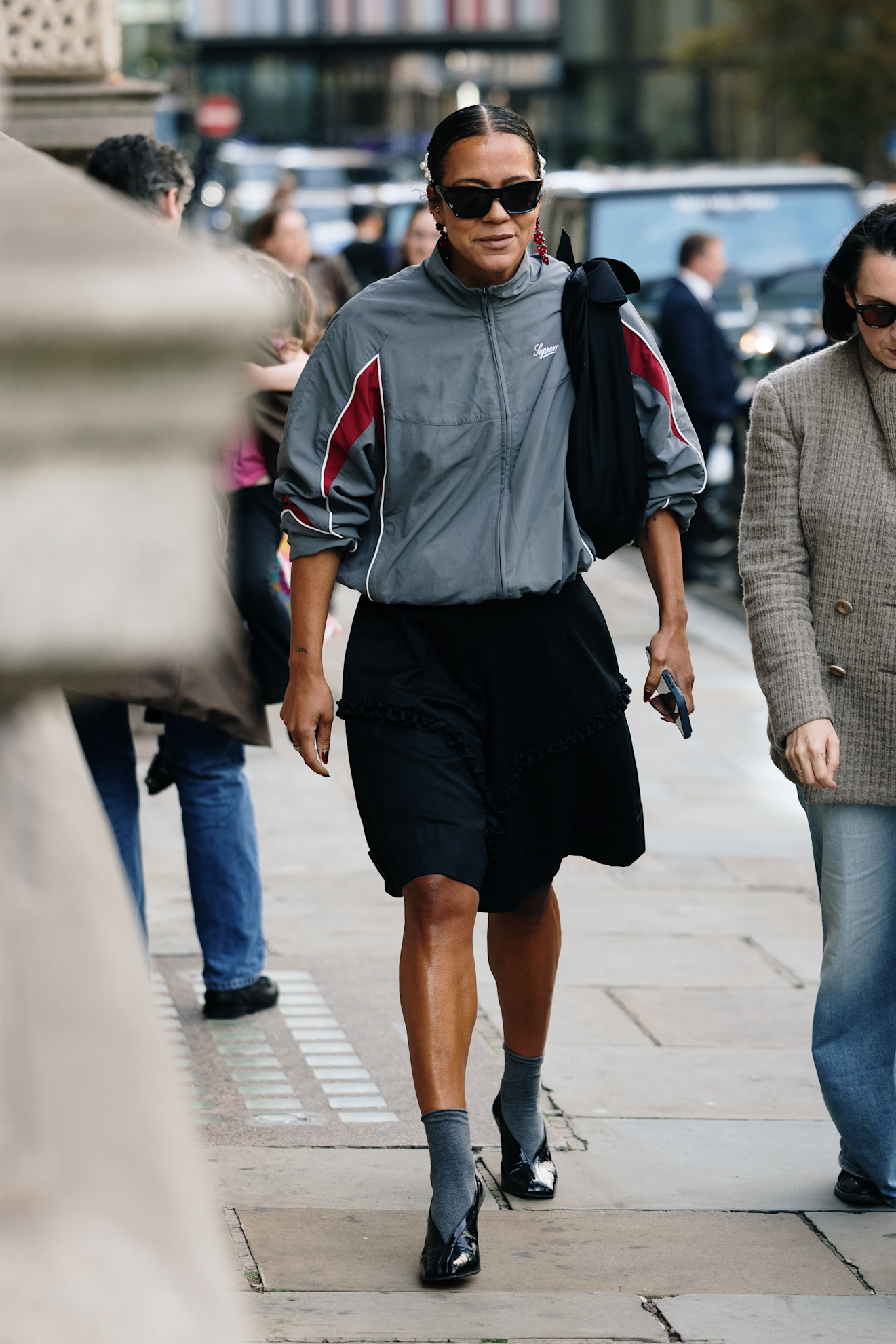 woman wearing sporty zip-up, skirt, and heels