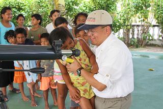 Schoolchildren from a primary school on on Tatakoto Atoll in French Polynesia look through telescope.