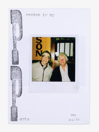 A polaroid photo of two men glued on a piece of paper.