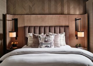 a bedroom with a brown feature wall and lights on