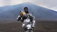 man in protective gear stands at the foot of a volcano