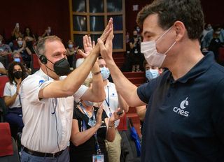 NASA Associate Administrator Thomas Zurbuchen and French space agency head Philippe Baptiste celebrate confirmation that the James Webb Space Telescope successfully deployed its solar arrays on Dec. 25, 2021.