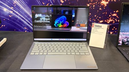 Lenovo Project Aeroblade laptop on display table, showing colorful abstract artwork and &ldquo;Productivity Without Compromise&rdquo; beside an information card.