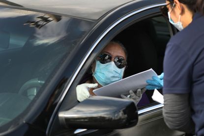 A person in their car arrives to receive an unemployment application being given out by City of Hialeah employees in front of the John F. Kennedy Library on April 08, 2020 in Hialeah, Florida