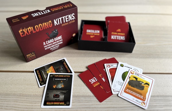 En öppnad förpacknning av spelet Exploding Kittens på ett bord.