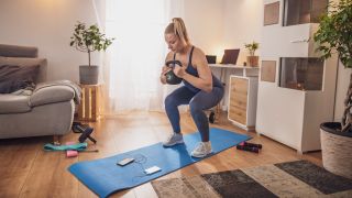 Woman performs kettlebell goblet squat at home