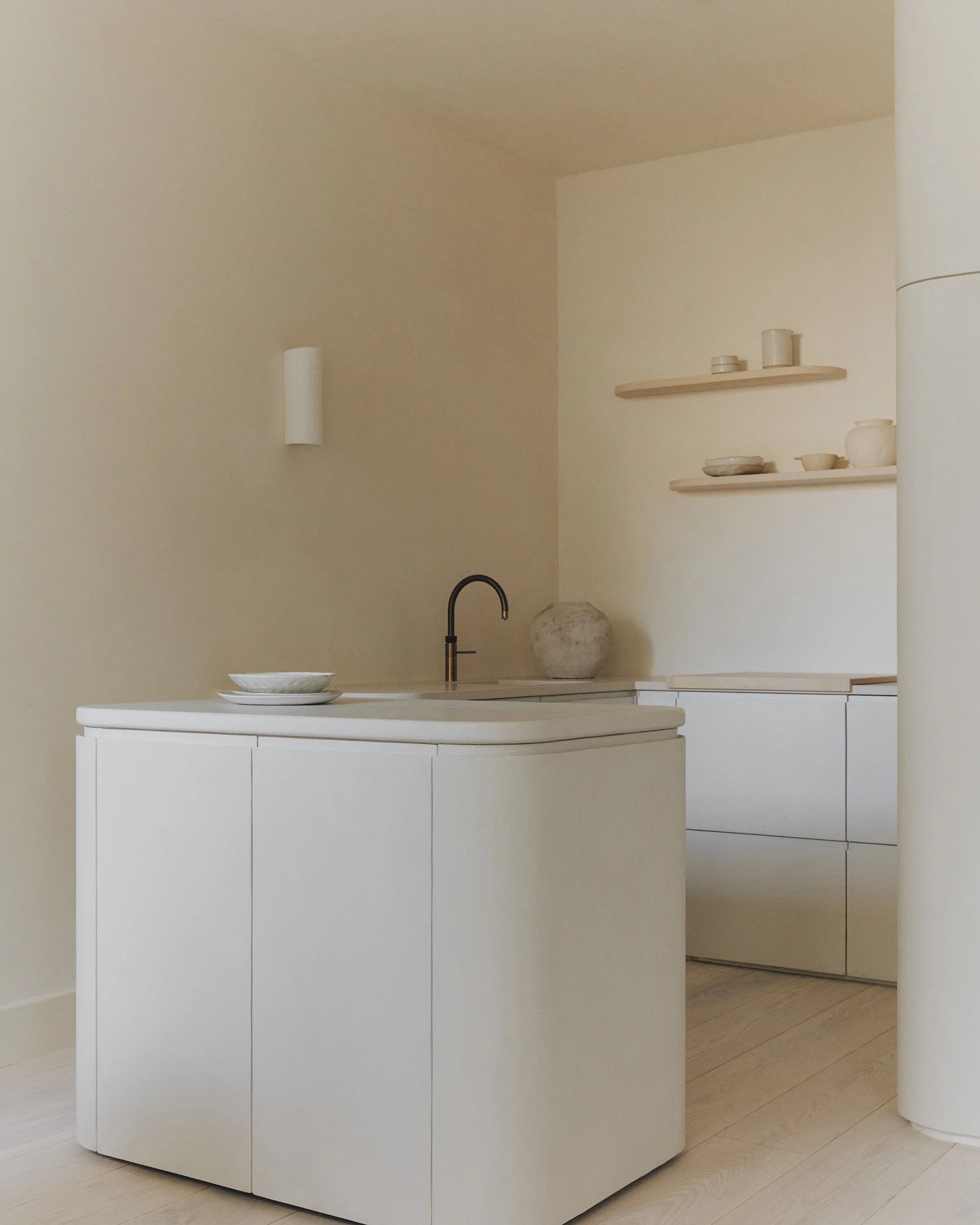 kitchen with plain cream walls and white cabinets with curved corners