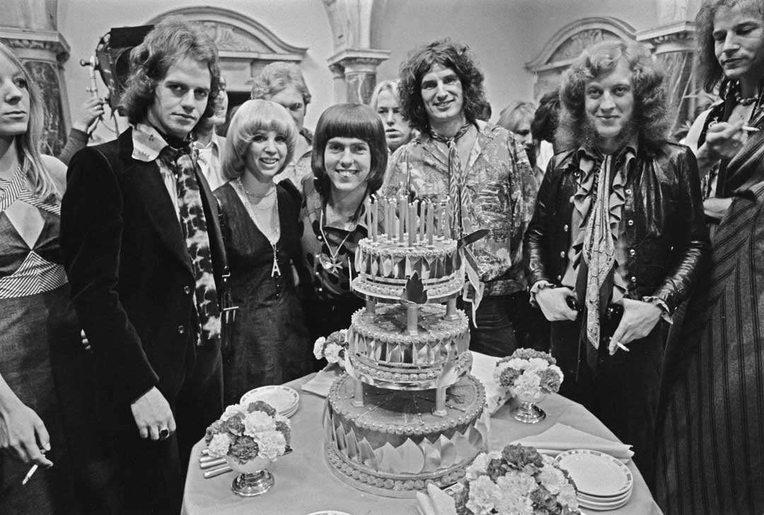 Slade during the film of Slade In Flame, standing around a multi-tiered cake with cast members