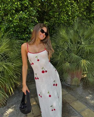 Influencer wears a cherry print dress.