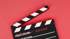 Photo collage of a filmmaker's clapboard on a red background. The word "Hollywood" is scratched out from it, and replaced by the Chinese name of China's Film Administration.