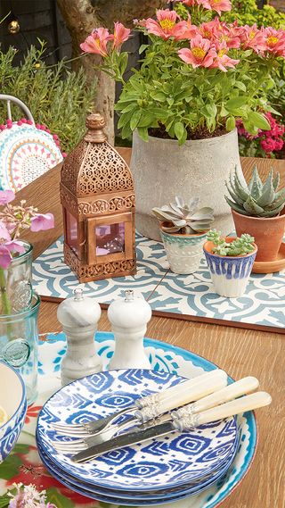 Moroccan tiles and lantern, cutlery and plates with blue and white pattern.