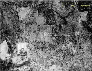 this 1934 aerial photograph taken of an area in Preston, Conn., shows a farmstead -- cleared fields, forest, stone walls or fences, a house, a barn and other outbuildings, and a road running through the farm.
