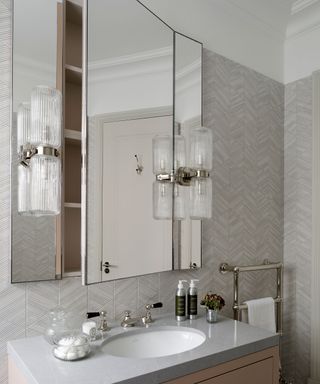 A mirrored wall cabinet with shelving above a sink and vanity unit