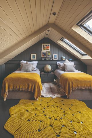 A children's bedroom in a loft conversion with bright yellow bedding and a yellow rug