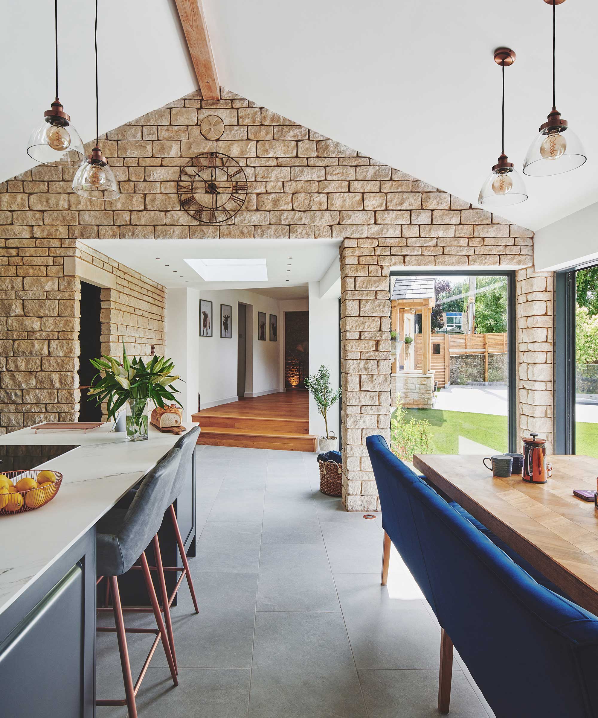 side extension to a stone cottage with an exposed stone wall, modern glazing, navy blue kitchen and dark grey tiled floor