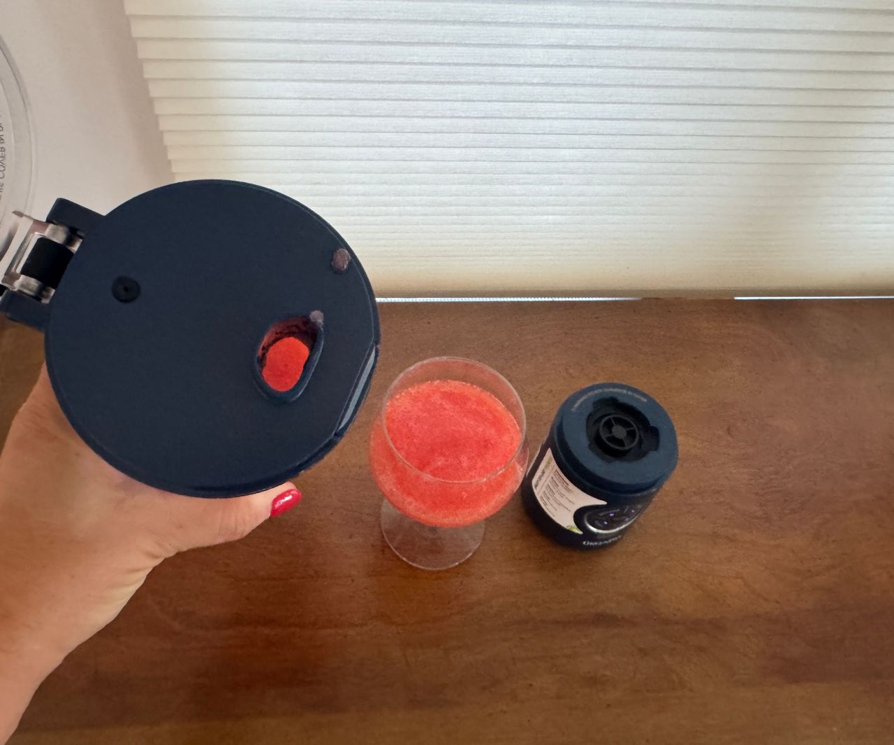A close up of the drinking spout after pouring a pink drink from the portable blender into a glass.