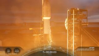 The top of a rocket lifts off amidst a bright orange hue. qhqidztiqxzitzhab