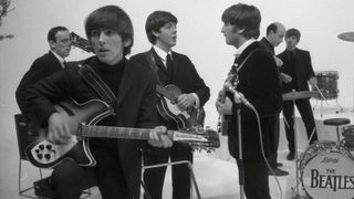 Harrison with his Rickenbacker 360/12 on the set of the Beatles’ 1964 film, A Hard Day’s Night. (From left) Actor John Junkin, Harrison, Paul McCartney, John Lennon, director Richard Lester and Ringo Starr