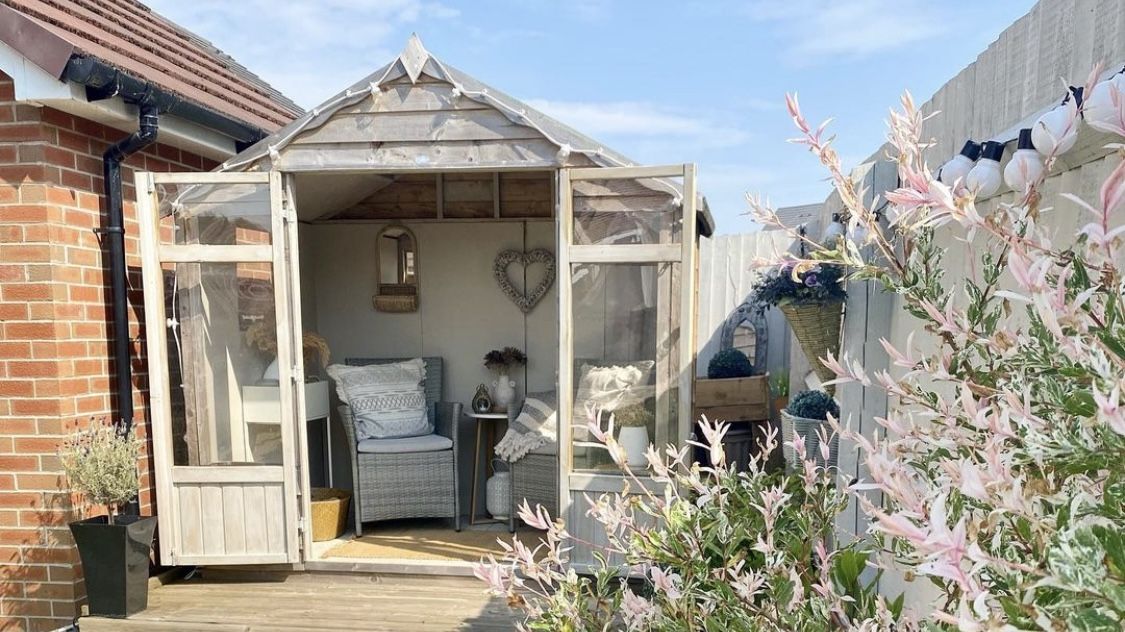 Summer house in garden with planters and patio area