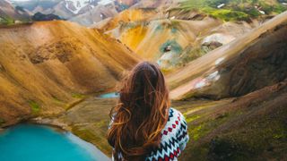 Woman traveler enjoying the view of scenic colorful rainbow mountains and turquoise lake in the wilderness