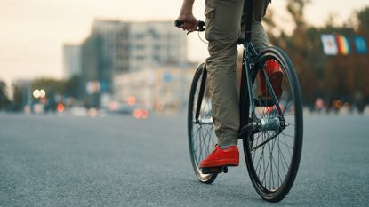 Image shows a person cycling with a set of the best flat pedals for cycle commuters