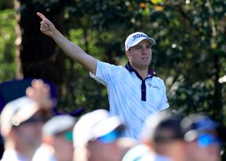 Justin Thomas points right after hitting a tee shot