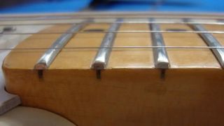 Close-up shot of a guitar fretboard featuring jumbo frets