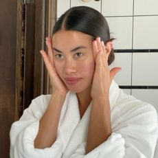 Woman in white dressing gown looking in mirror