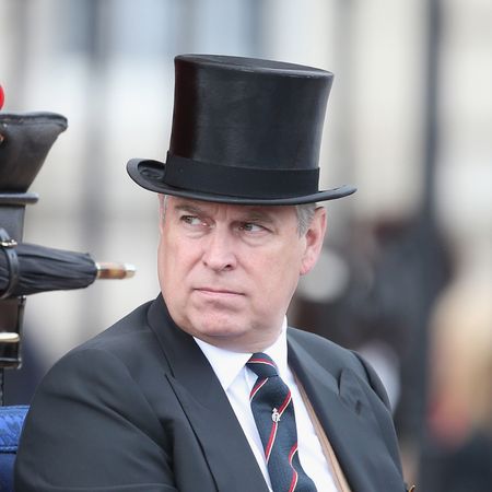 Prince Andrew rides in a carriage while wearing a top hat and a suit