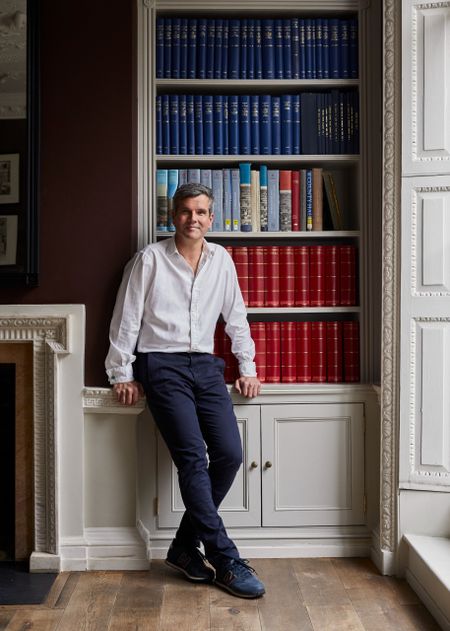 Ben Pentreath leaning against a bookcase in a kitchen