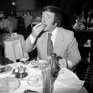 Terry Wogan samples an oyster at a reception.