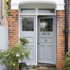house having exposed brick wall white door and green plants in pots