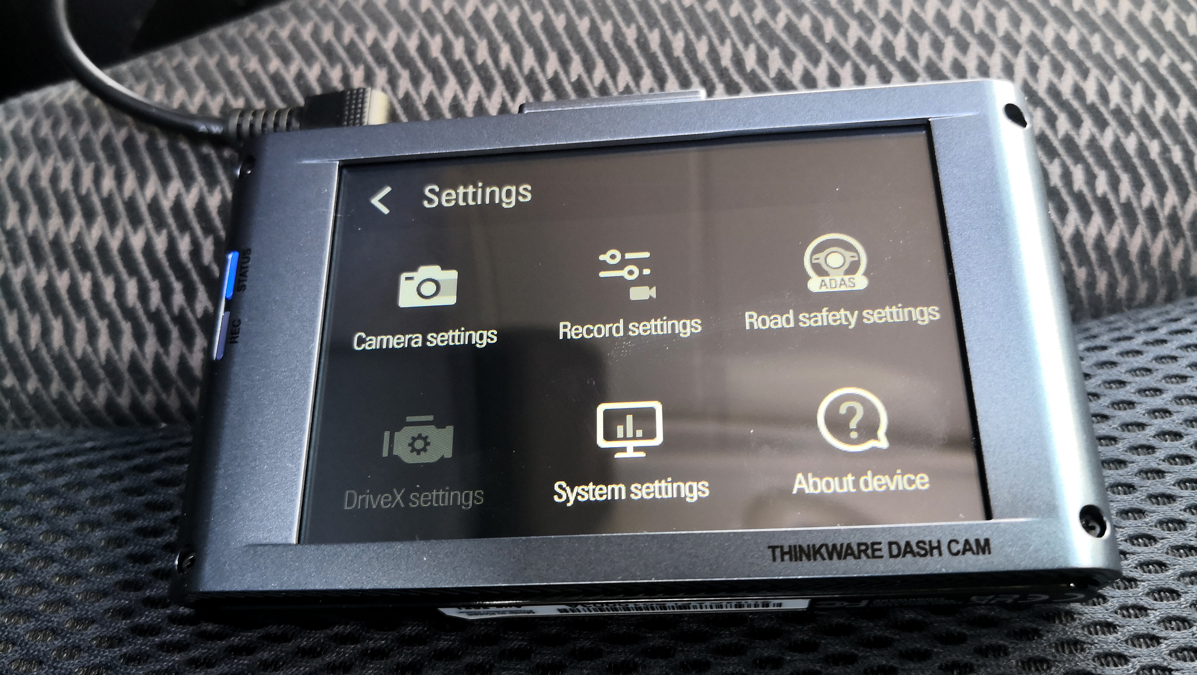 The Thinkware X1000 dash cam sitting on a car seat