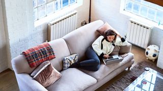 Woman lying down with laptop on sofa at home