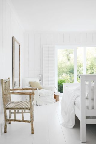 Rustic white bedroom with panelled walls and rustic wooden furniture