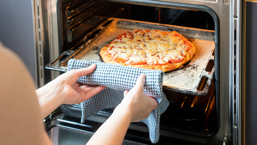 Taking a pizza out of an oven