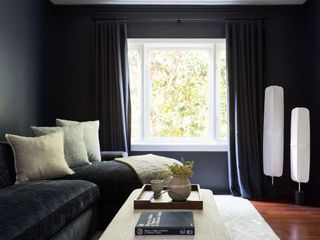 Small room painted black with navy curtains